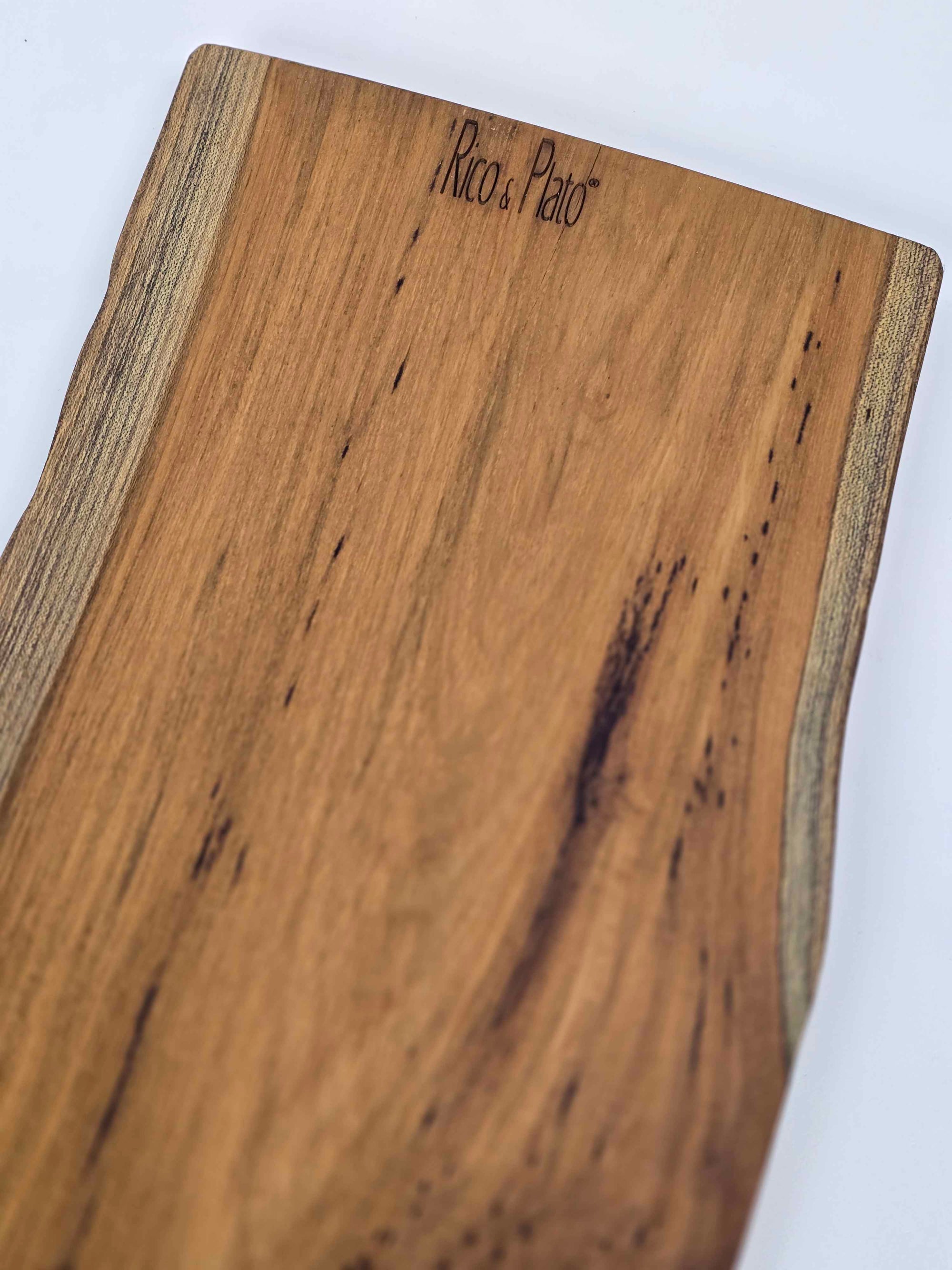 Wooden cutting board with 'Rico & Plato' branding on a white background