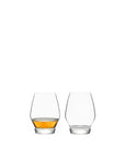 Two bourbon glasses, one filled with a amber liquid, on a white background