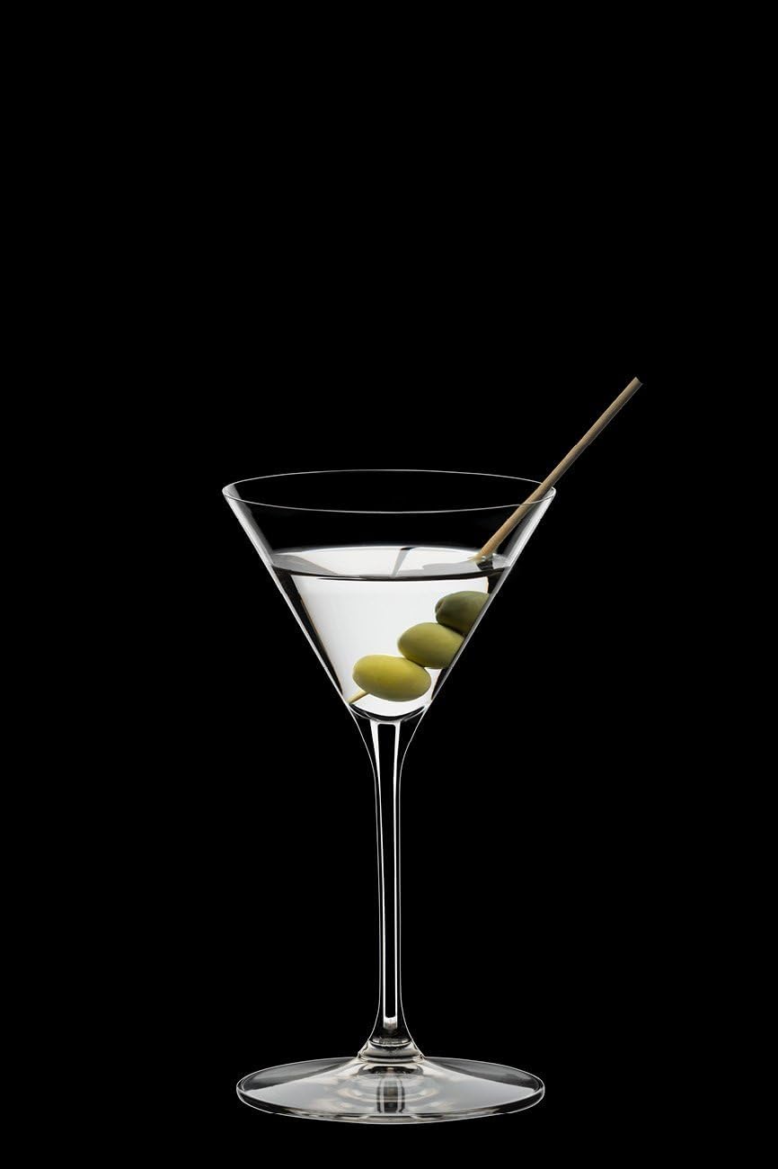 Martini glass with olive and cocktail stick on a black background