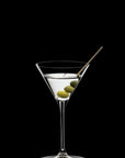 Martini glass with olive and cocktail stick on a black background
