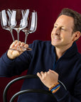 Man holding three wine glasses against a red background