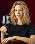 Woman holding a glass of red wine against a dark background