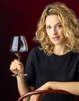 Woman holding a glass of red wine against a dark background