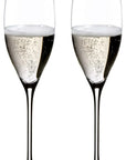 Two clear champagne flutes filled with sparkling champagne, shown side by side on a plain white background.