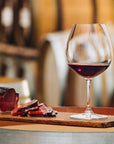 Glass of red wine on a wooden board with sliced meat, blurred background