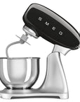 Smeg stand mixer with black control panel slanted open on a white background