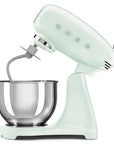 Light green stand mixer slanted open with a mixing bowl on a white background