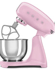 Pink stand mixer slanted open with a mixing bowl on a white background