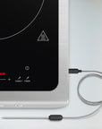 Induction cooktop with digital display and digital temperature probe on a white background