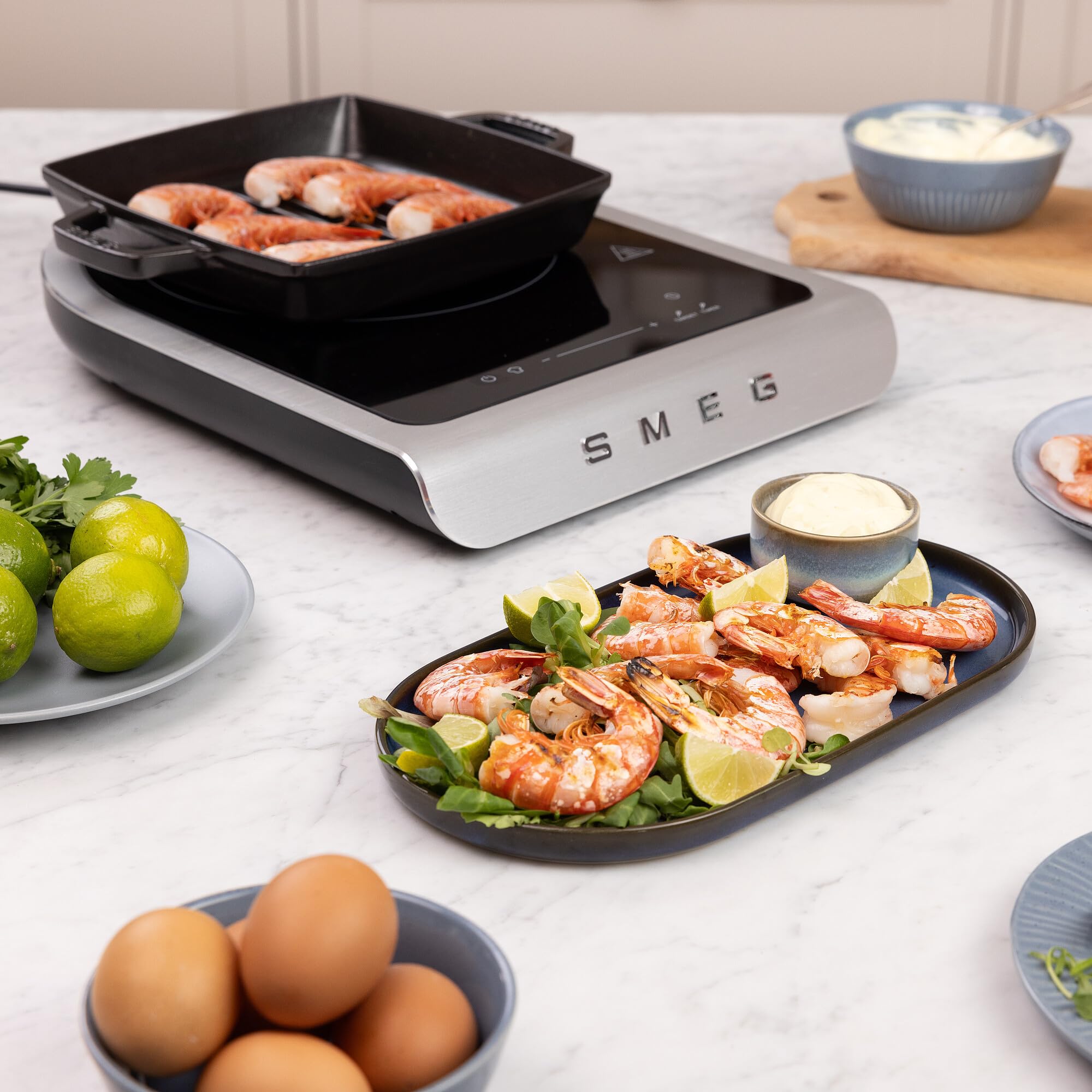 Smeg induction cooktop with shrimp and vegetables on a kitchen counter