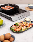 Smeg induction cooktop with shrimp and vegetables on a kitchen counter