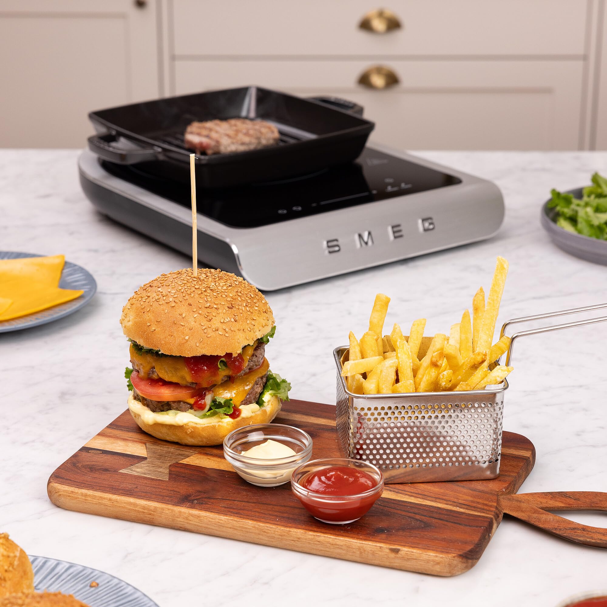 Burger and fries on a kitchen counter with a Smeg induction cooker in the background