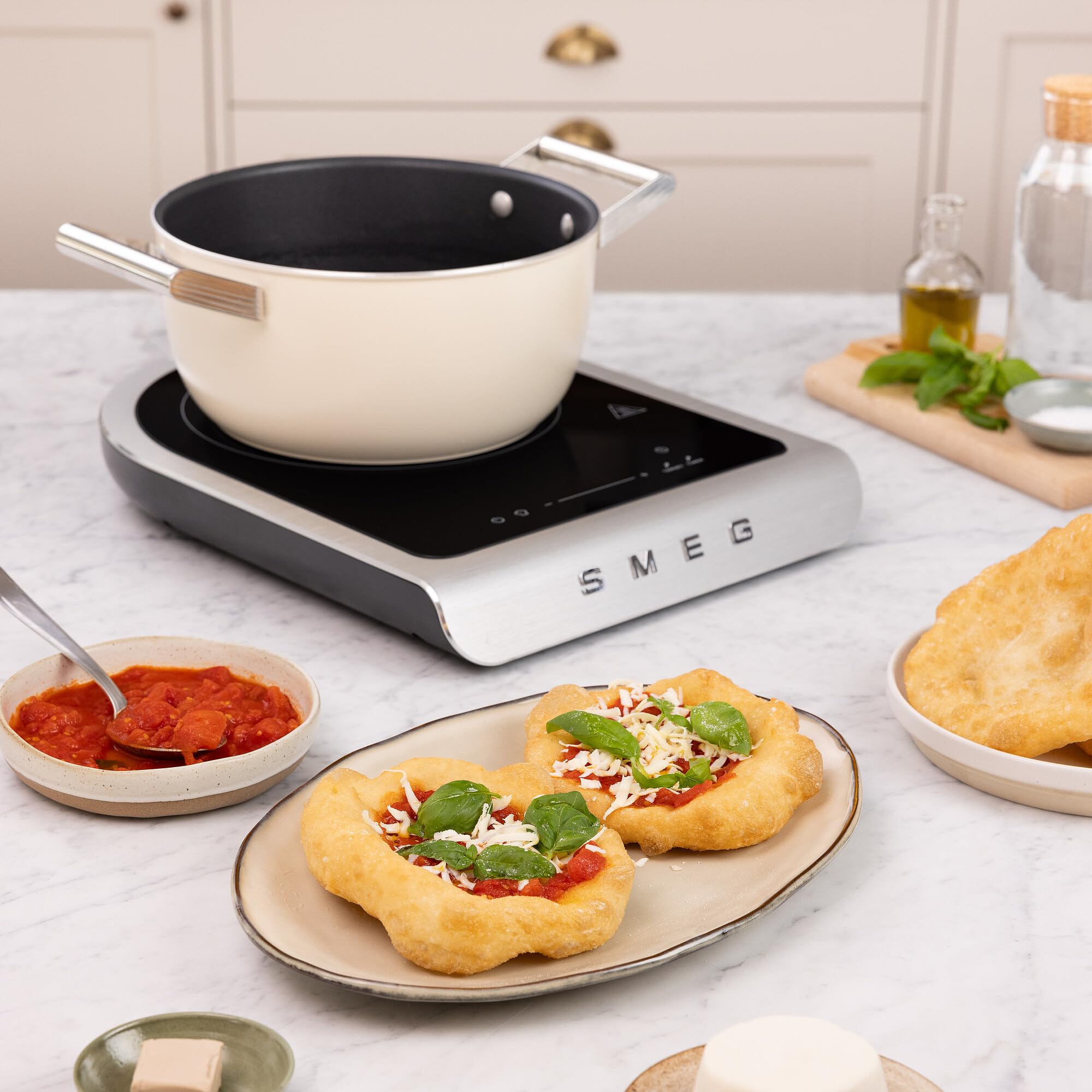 Induction cooktop with a pot on a kitchen counter, surrounded by food items.