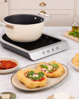 Induction cooktop with a pot on a kitchen counter, surrounded by food items.