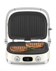 Cream Smeg grill with two steaks on a white background
