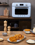 Kitchen scene with a pastel blue Smeg oven, wooden table, and plates of food.