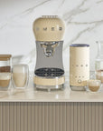 Cream Smeg coffee machine on a kitchen counter with various coffee items.
