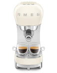 Cream-colored SMEG espresso machine with two glass cups with coffee inside on a white background