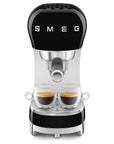 Black Smeg espresso machine with two glass cups with coffee inside on a white background