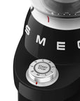 Black SMEG coffee grinder with control knob and brand logo on a white background