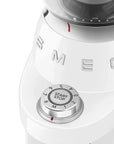 White coffee grinder with control knob and 'Smeg' branding on a white background