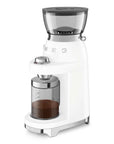 White coffee grinder with coffee grinds inside container on a white background
