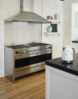 Modern kitchen with stainless steel stove and black countertop with a white Smeg electric kettle