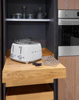 Kitchen interior with a toaster on a wooden counter, stainless steel refrigerator, and oven.