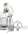 Cream and silver stand mixer with attachments on a white background