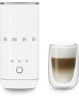 White milk frother with a glass of layered coffee on a white background