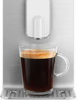 White SMEG espresso machine with a glass of espresso on a white background