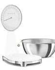 White Smeg kitchen digital scale with a metal bowl on the side displayed on a white background