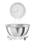Front view of white Smeg digital kitchen scale with a silver bowl displayed on a white background
