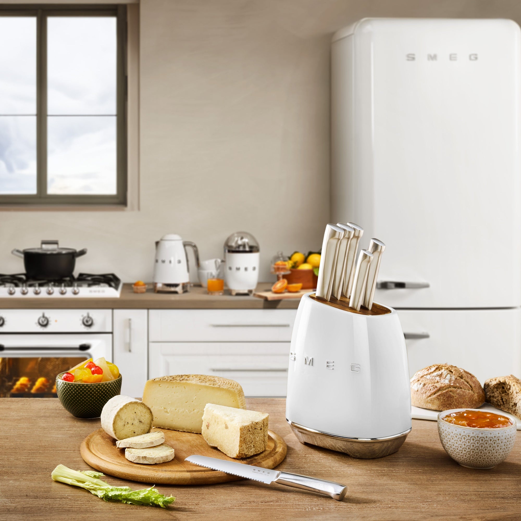 Modern kitchen with a knife holder, cheese, and fruits on a wooden table.