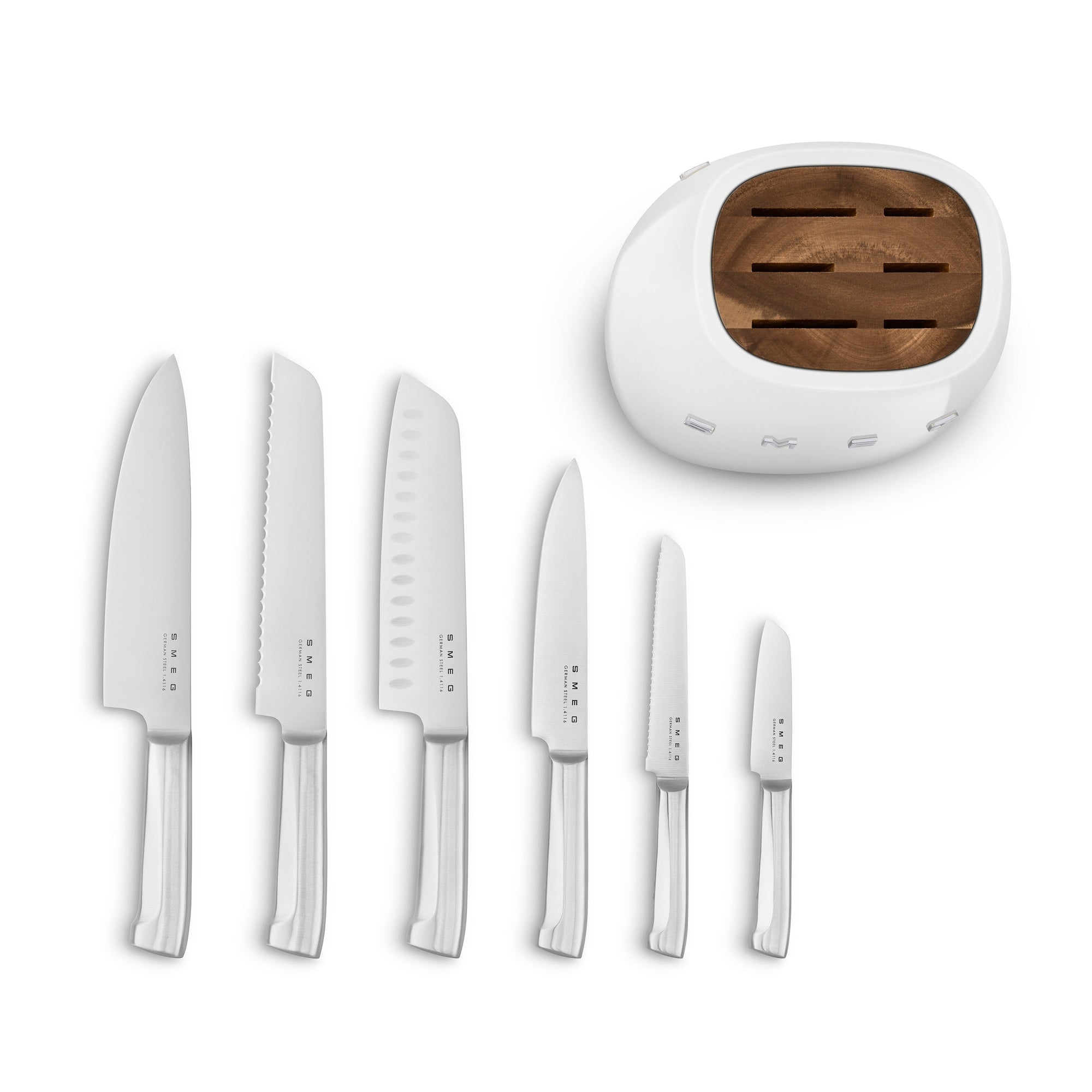 Top view of white Smeg knife block next to an assortment of knives lined in a row displayed on a white background