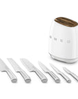 White Smeg knife block next to an assortment of knives lined up in a row displayed on a white background