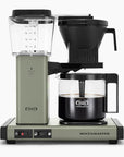Front view of green Moccamaster coffee maker with coffee filled carafe on a white background