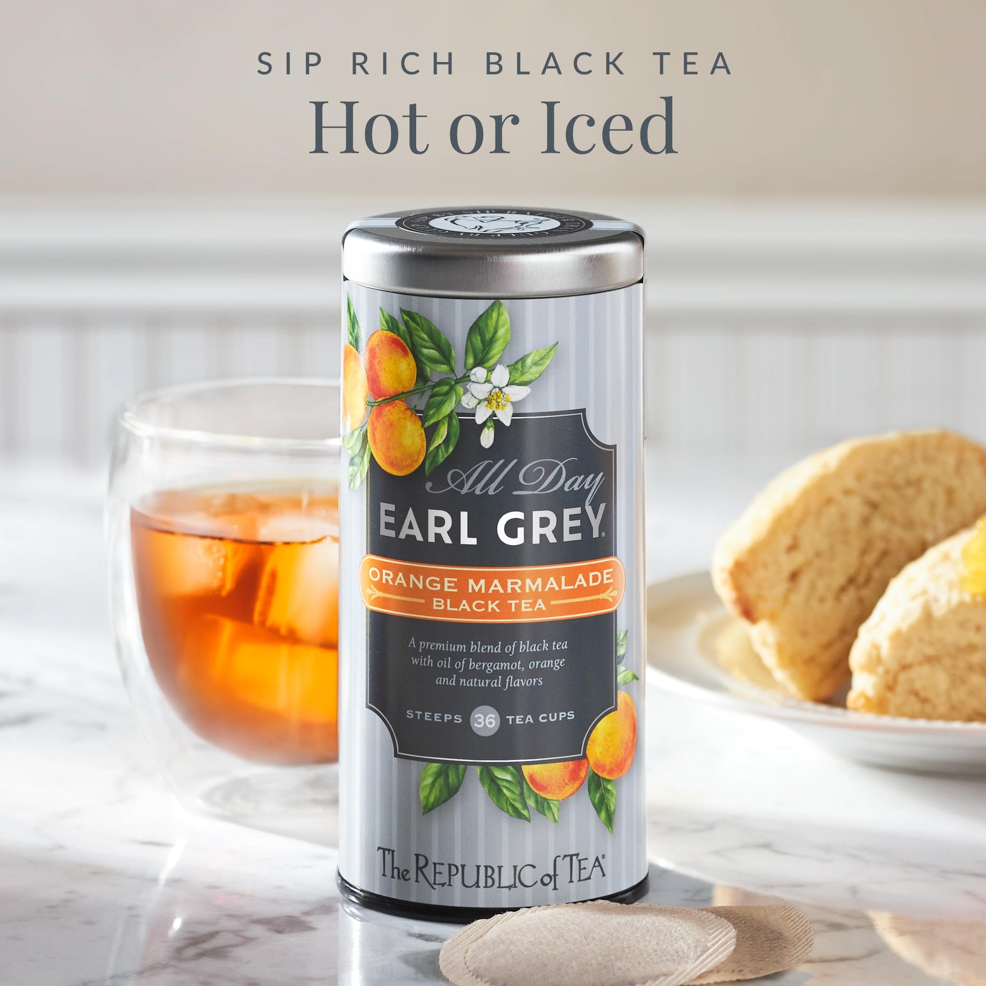 Canister of 'All Day Earl Grey' tea with a glass of tea and cookies on a marble surface.