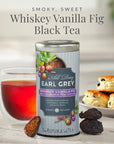 Tea canister labeled 'All Day Earl Grey Whiskey Vanilla Fig Black Tea' with a glass of tea and biscuits in the background.