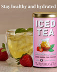 Pink can of 'Strawberry Basil' iced tea with a glass of iced tea and strawberries on a wooden surface.
