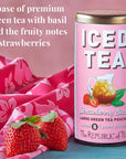Pink canister of 'Strawberry Basil' iced tea with strawberries on a pink floral cloth background