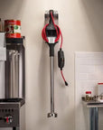 Wall-mounted red and black electric blender in a kitchen setting.