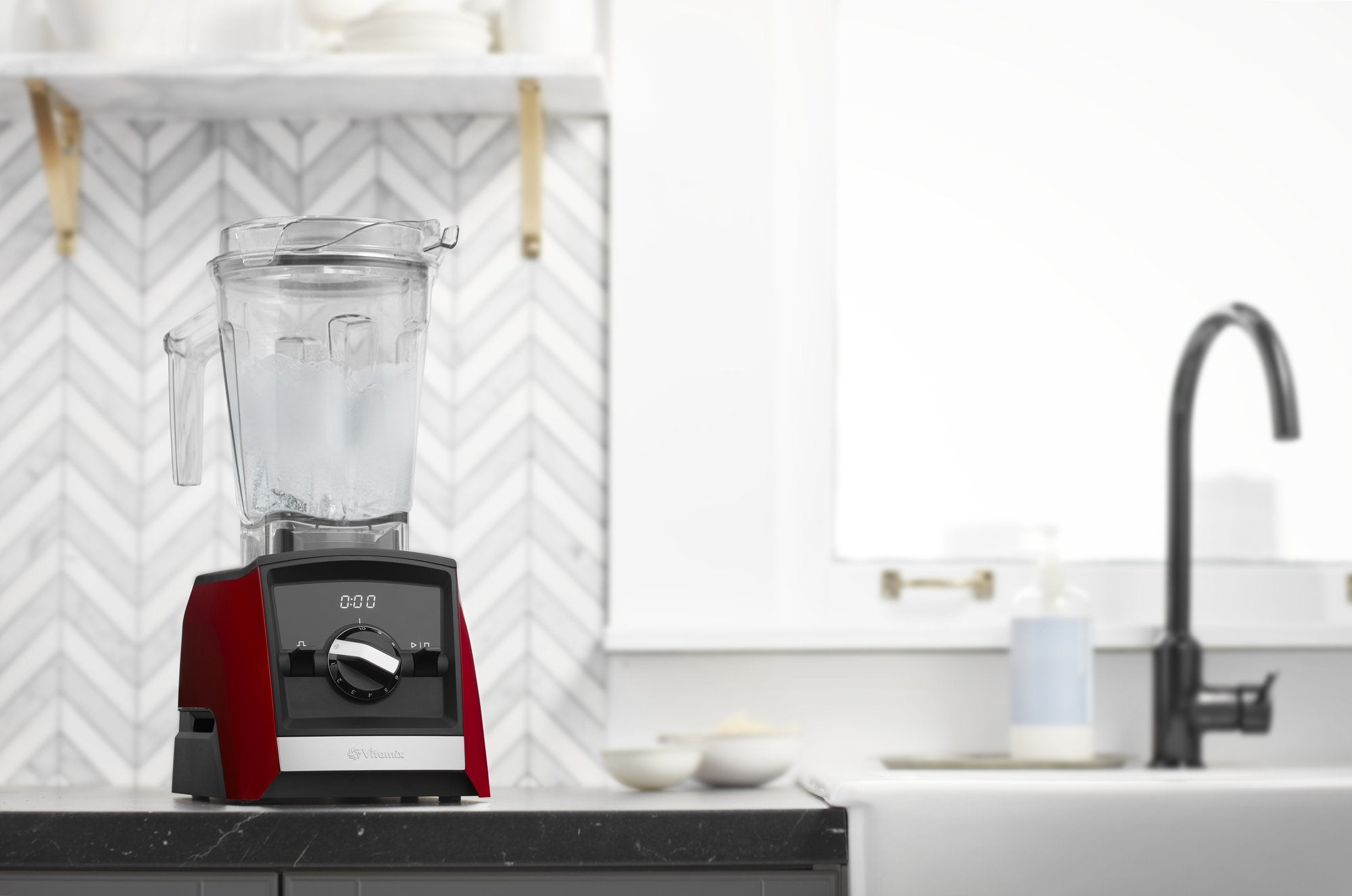 Red blender on a kitchen counter with a white tiled wall in the background