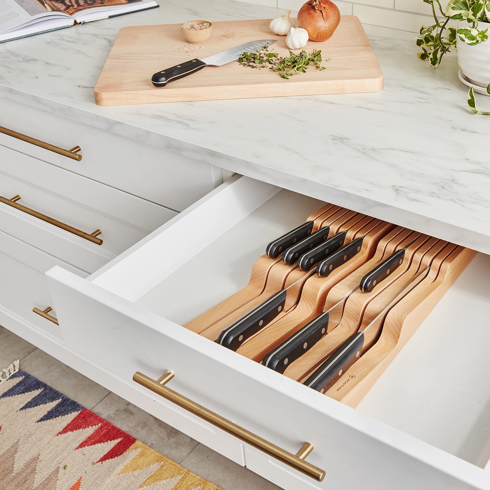 Open kitchen drawer with wooden knife block and cutting board on countertop