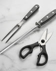 Set of kitchen utensils including a fork, knife, and scissors on a marble surface