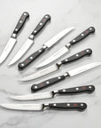 Set of seven steak knives with black handles on a marble surface
