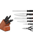 Set of knives and a pair of scissors next to a knife block set on a white background