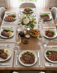 Dining table set for a meal with plates of food, glasses, and cutlery.